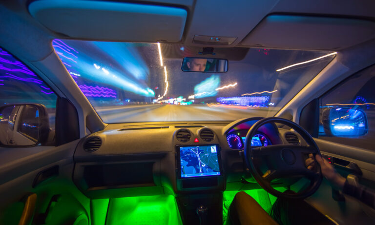 The man drive a vehicle on the night road. Inside view